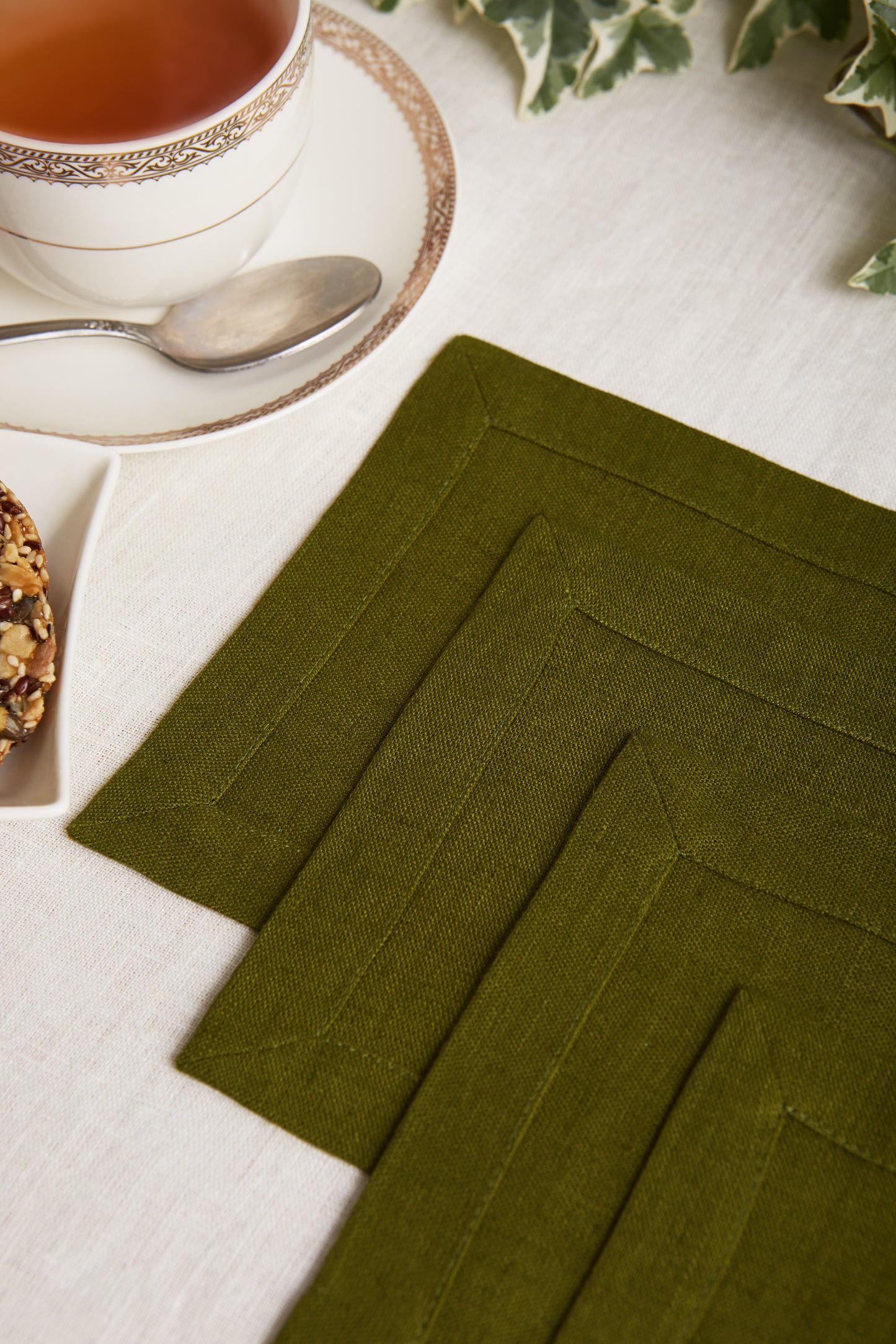 A set of 4 square linen coasters in dark khaki with mittered corners, made from zero wastes